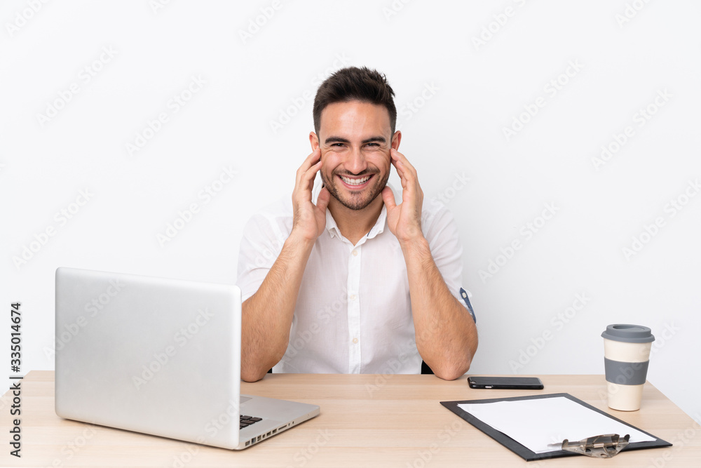 Young business man with a mobile phone in a workplace laughing Young business man with a mobile phone in a workplace laughing
