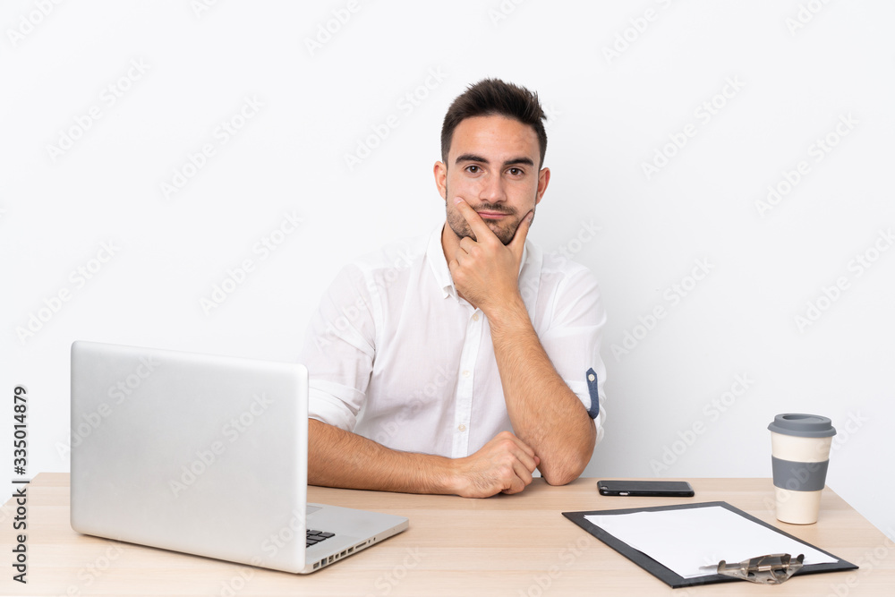Young business man with a mobile phone in a workplace thinking an idea Young business man with a mobile phone in a workplace thinking an idea