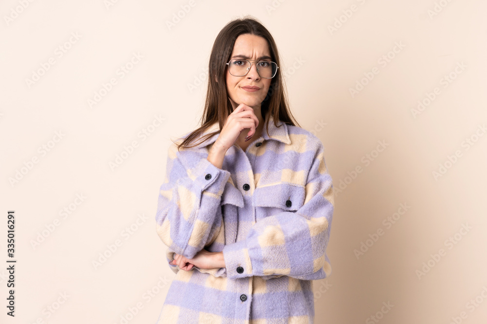 Young woman over isolated beige background having doubts and thinking Young woman over isolated beige background having doubts and thinking