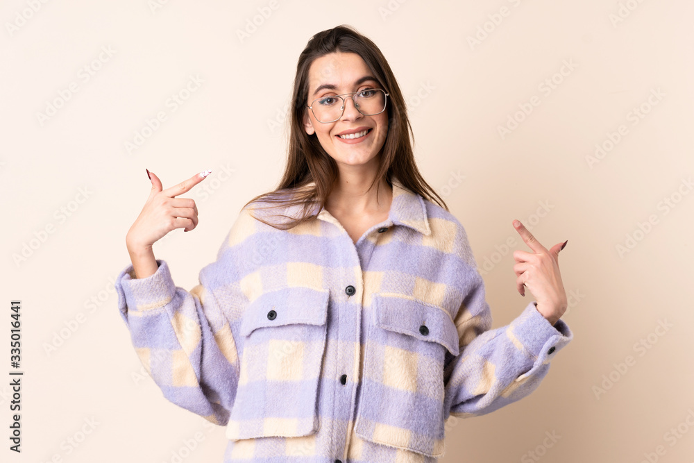 Young woman over isolated beige background giving a thumbs up gesture Young woman over isolated beige background giving a thumbs up gesture