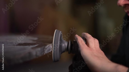  Worker in a green jacket and beard polishes a marble table in a factory. Super Slow Motion