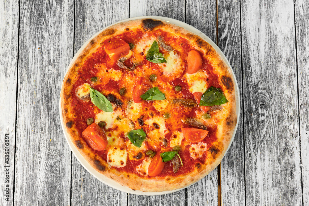 Pizza with tomatoes, cheese and basil on wooden background. Closeup, top view Pizza with tomatoes, cheese and basil on wooden background. Closeup, top view