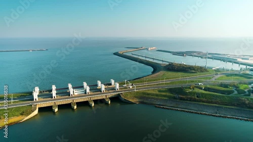 Enclosure Dam (Afsluitdijk): Cars Driving on the Long Road of the Dam, Large Cargo Ship in the Distance - Friesland, Netherlands / Holland – 4K Drone Footage photo