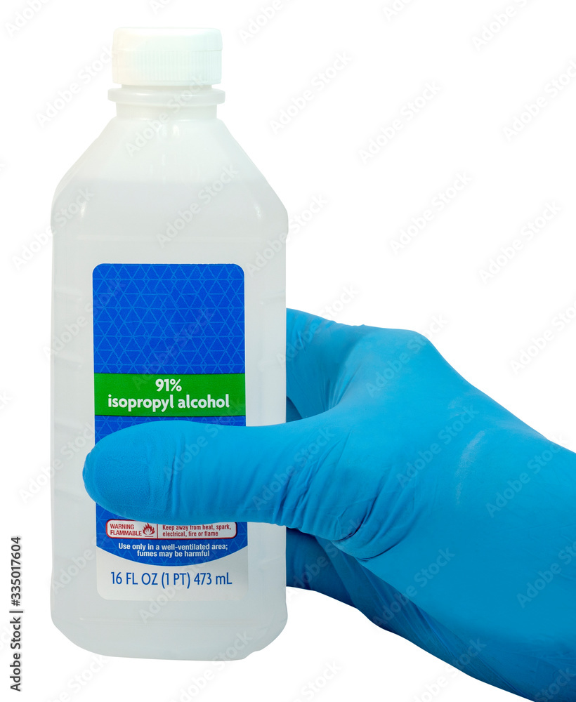 Hand wearing blue surgical glove holding bottle of isopropyl alcohol