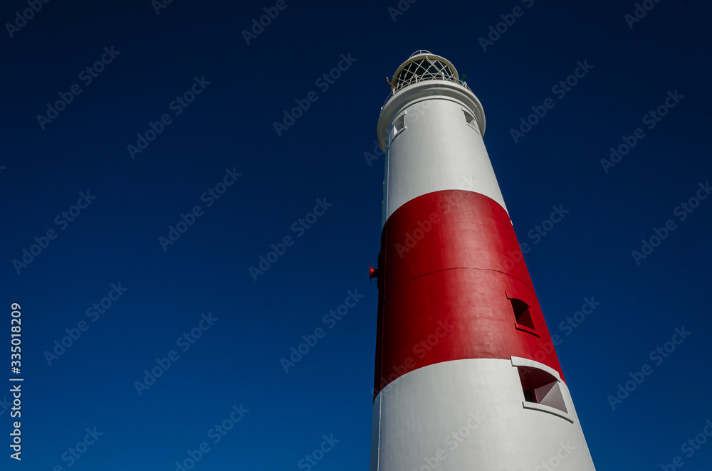 Looking up at Portland Bill lighthouse against the contrast of a deep blue summer sky, Isle of Portland, Dorset, UK