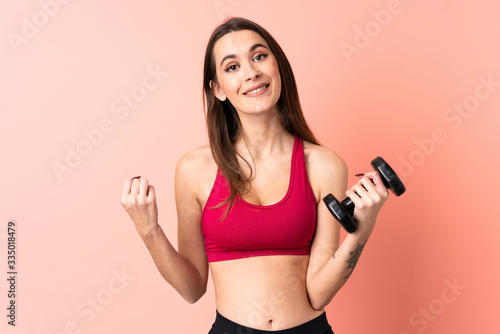 Young sport woman making weightlifting over isolated pink background pointing to the side to present a product