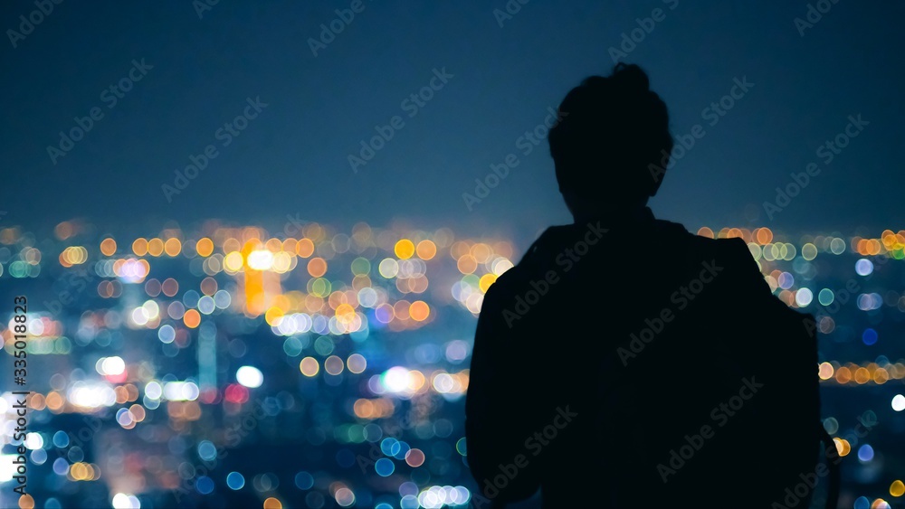 Silhouette Man looking to beautiful color of city night light from top of building at bangkok Thailand. Back view of young man.