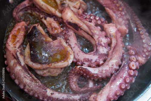 The large octopus is fried on a frying pan, Feelers of violet color, close-up