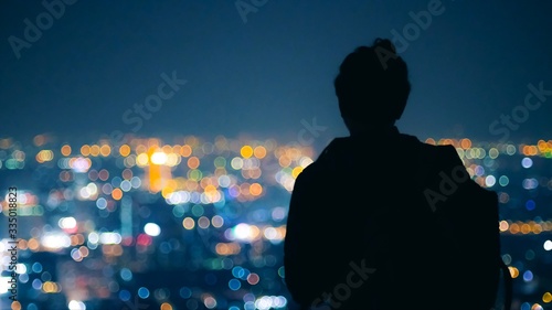Silhouette Man looking to beautiful color of city night light from top of building at bangkok Thailand. Back view of young man.