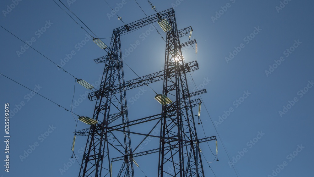 Metal power transmission line support, view from below, the sun and the rays through the structure Metal power transmission line support, view from below, the sun and the rays through the structure