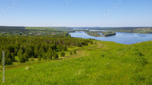 country road on a hillside overgrown with grass and sparse small trees on the banks of the Kama River