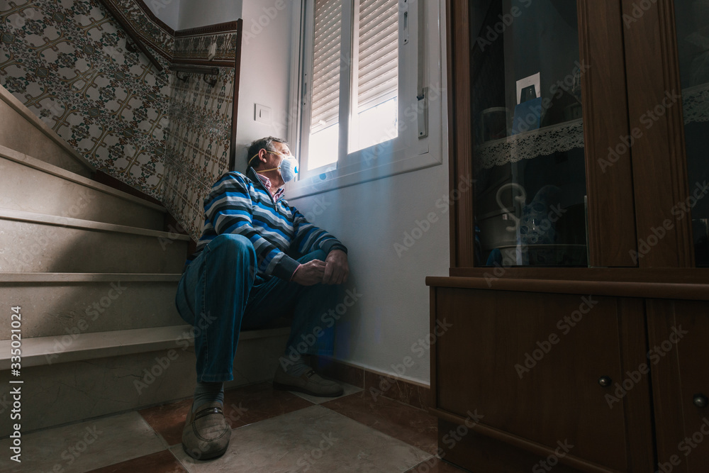 Selective focus of man with a mask confined in quarantine to prevent coronavirus spread to the window. Selective focus of man with a mask confined in quarantine to prevent coronavirus spread to the window.