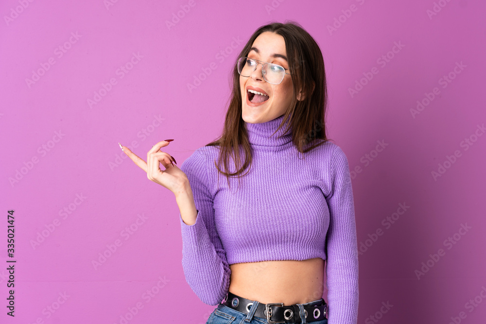 Young woman over isolated purple background intending to realizes the solution while lifting a finger up Young woman over isolated purple background intending to realizes the solution while lifting a finger up