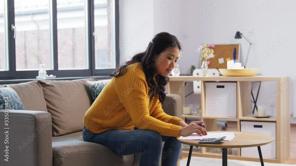 accounting, taxes and finances concept - young asian woman with papers and calculator at home accounting, taxes and finances concept - young asian woman with papers and calculator at home