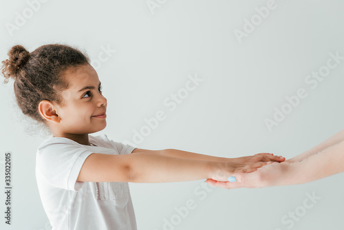 mother holding hands with happy and adopted african american kid isolated on white
