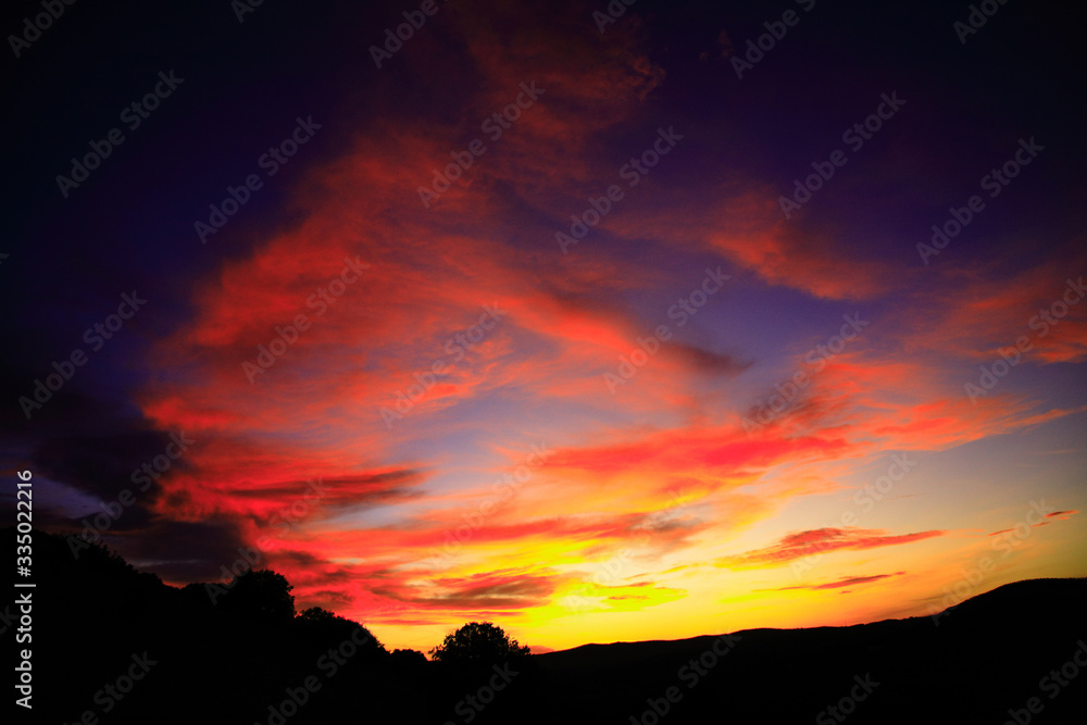 Dark orange sky with clouds in the countryside.