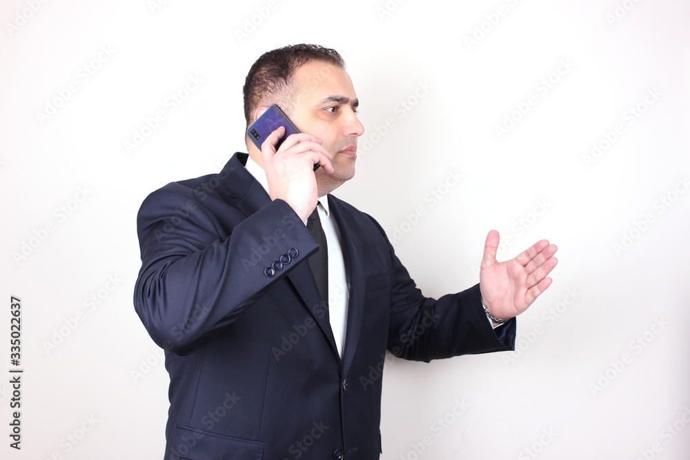 Serious businessman in a suit and tie arguing by the phone. Business concept isolated Serious businessman in a suit and tie arguing by the phone. Business concept isolated