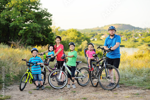 Young large family on bicycles in the Park against the background of greenery and trees.