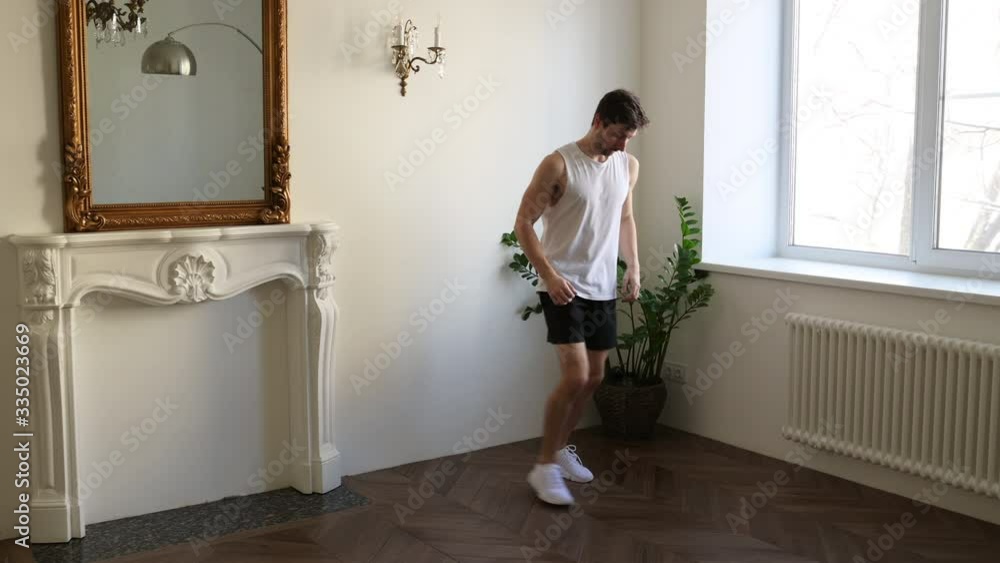 Strong Athletic Man in T-shirt and Shorts is Doing Forward Lunge Exercises at Home in His Spacious and Bright Apartment with Minimalistic Interior Strong Athletic Man in T-shirt and Shorts is Doing Forward Lunge Exercises at Home in His Spacious and Bright Apartment with Minimalistic Interior