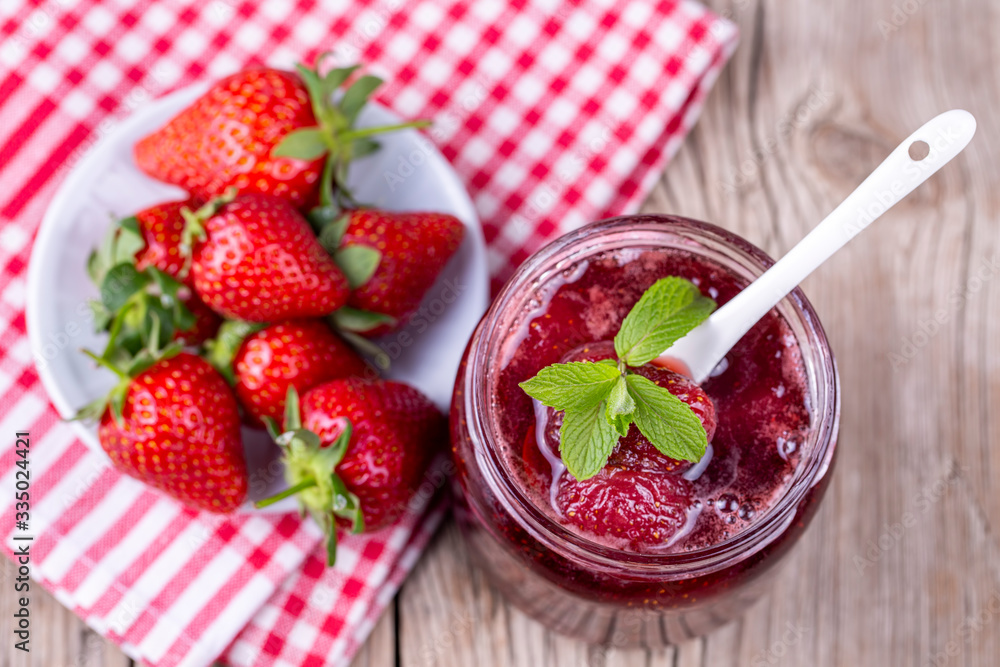 Homemade delicious strawberry jam and strawberry on a rustic wooden table Homemade delicious strawberry jam and strawberry on a rustic wooden table