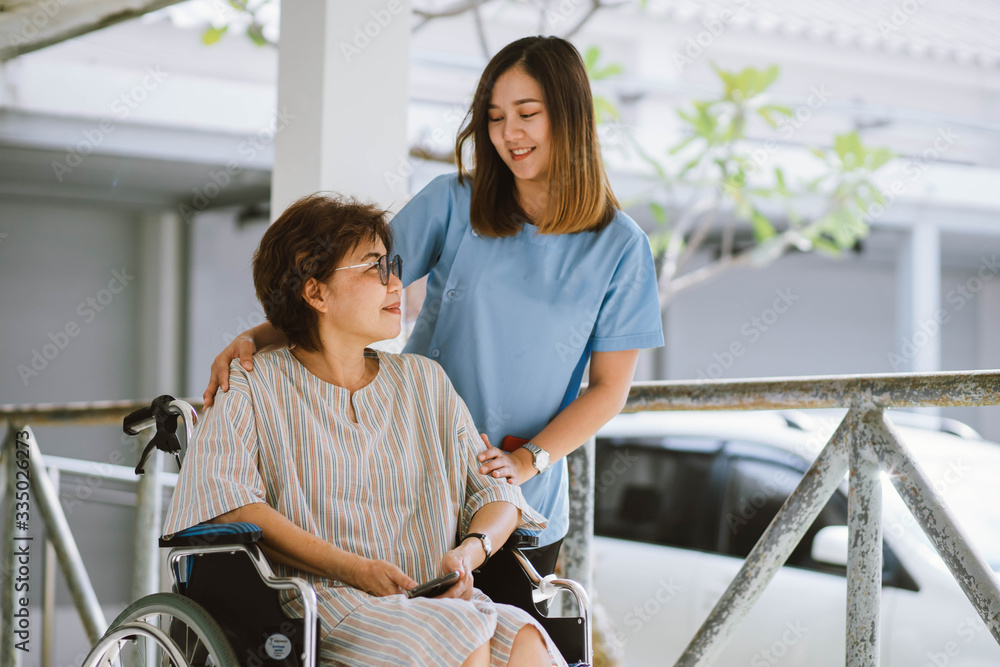 Smiling physiotherapist taking care of the happy senior patient in wheelchair Smiling physiotherapist taking care of the happy senior patient in wheelchair