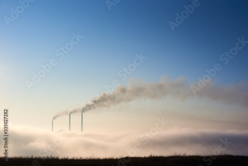 Φωτογραφία Tops of three smoking stacks of thermal power station on horizon taken from the