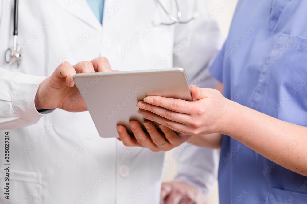 Doctor and nurse discussing patients tests at tablet computer in hospital Doctor and nurse discussing patients tests at tablet computer in hospital