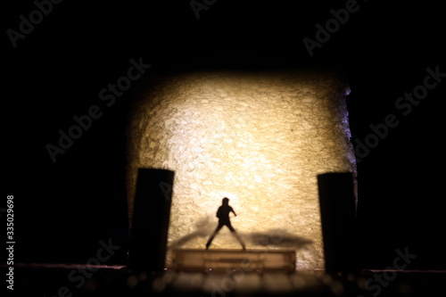Conceptual Photo  Silhouette Bassist or Guitarist in Action  at Fake Stage  Yellow Lighting