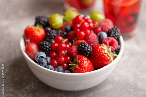 Bowl with fresh summer berries on a gray background.