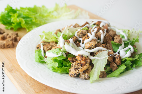 Classic Caesar salad with its ingredients: grilled chicken, croutons, lettuce and dressing sauce