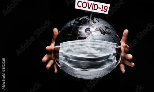 Hands holding globe sphere where shown white board COVID-19