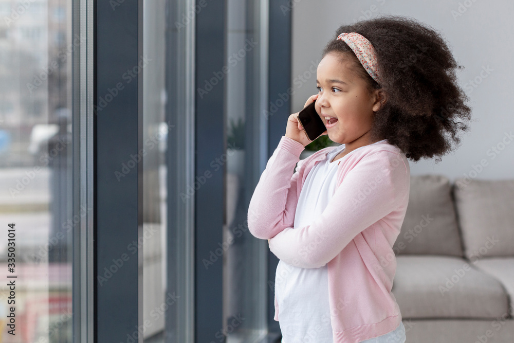 Cute little girl talking on the phone at home