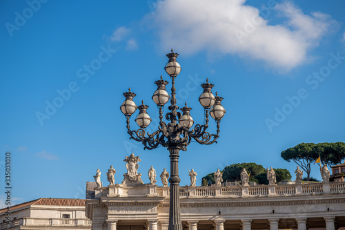 latarnia na plecyu Świętego Pitra w Watykanie. jedna z kilku ozdobnych, zabytkowych latarni . W tle piękne rzeźby otaczające cały plac