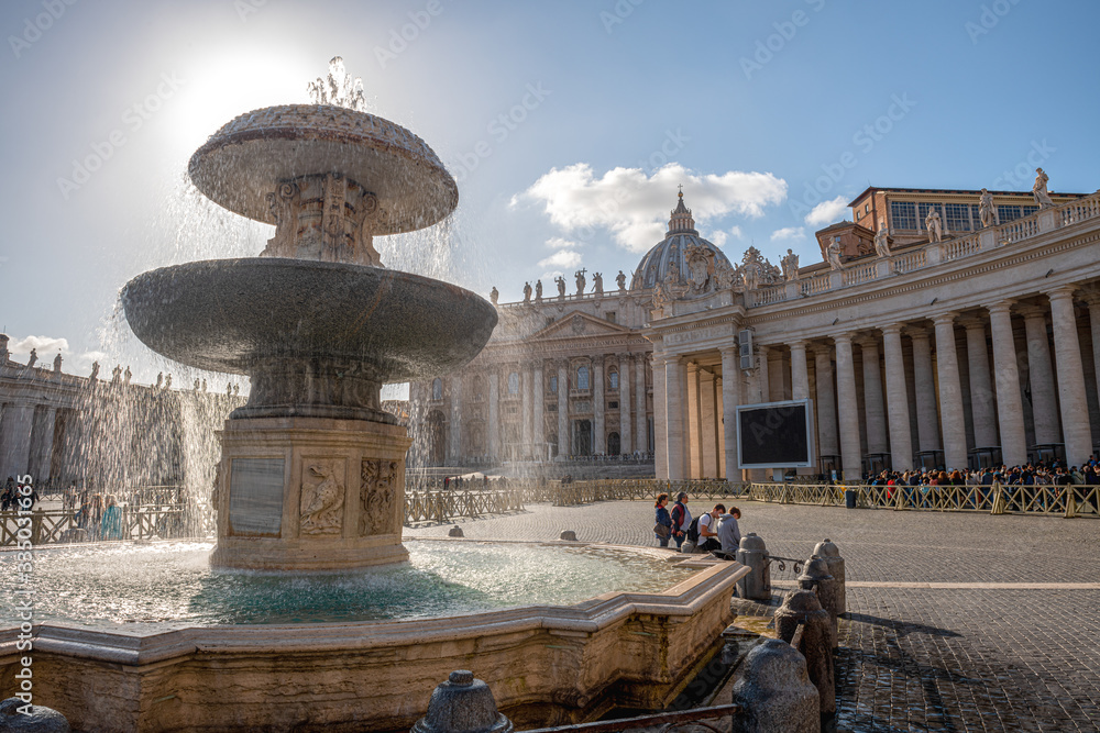 Zabytki na placu Św. Piotra w Watykanie. Na pierwszym planie ogromna fontanna, a w oddali widać bazylikę świętego Piotra, Włochy. - obrazy, fototapety, plakaty 