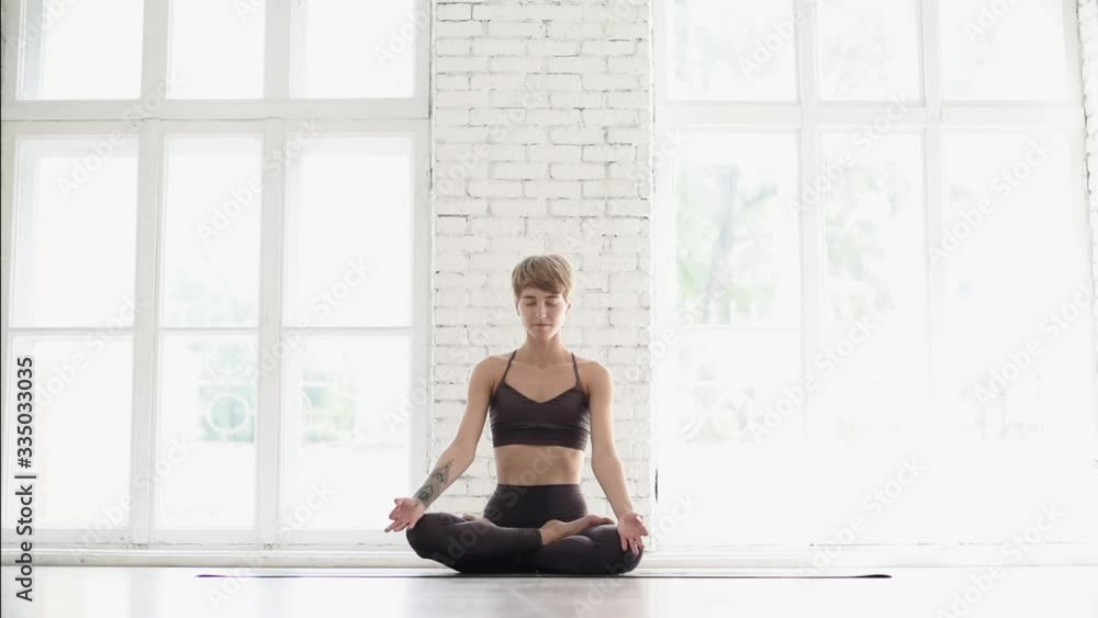 Young beautiful woman practicing yoga in yoga studio. Fit girl doing exercises and meditating at home. Harmony, yoga, balance, meditation, relaxation, healthy lifestyle concept Young beautiful woman practicing yoga in yoga studio. Fit girl doing exercises and meditating at home. Harmony, yoga, balance, meditation, relaxation, healthy lifestyle concept