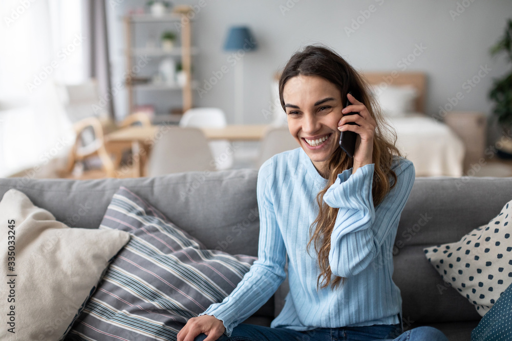 Woman emotionally talking on a mobile while sitting at home on the couch. Portrait of a positive girl. Woman emotionally talking on a mobile while sitting at home on the couch. Portrait of a positive girl.