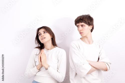 The young girl in a white sweatshirt is looking at the sky. She is praying and keeps his hands folded in the pray. The young boy stands next to him.