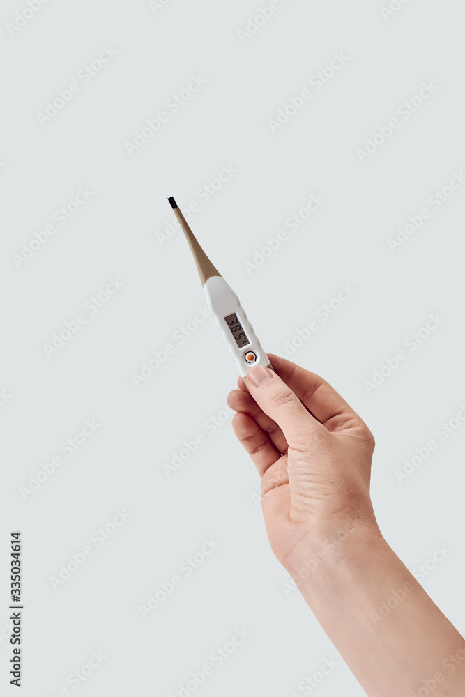 Vertical shot of female hand holding an electronic thermometer that shows 38.5 Celsius against white background Vertical shot of female hand holding an electronic thermometer that shows 38.5 Celsius against white background