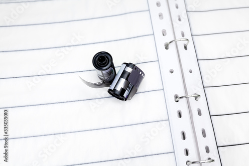 Rolls of film to analog camera which are laying on the photo album to store 35mm film. Analog photography basic kit. Film strip storage in special album.