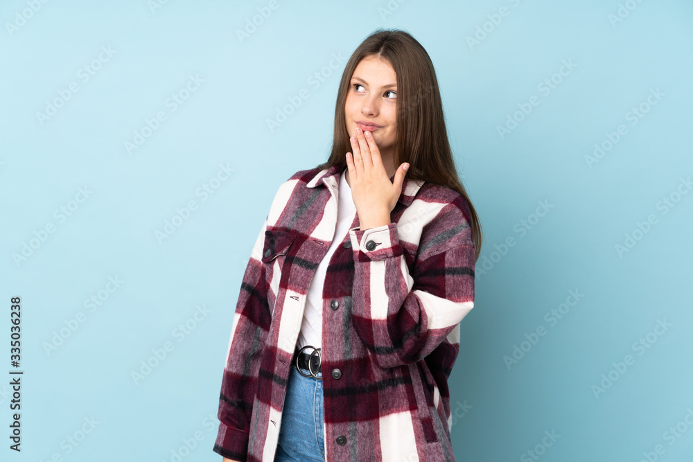 Teenager caucasian girl isolated on blue background looking up while smiling Teenager caucasian girl isolated on blue background looking up while smiling