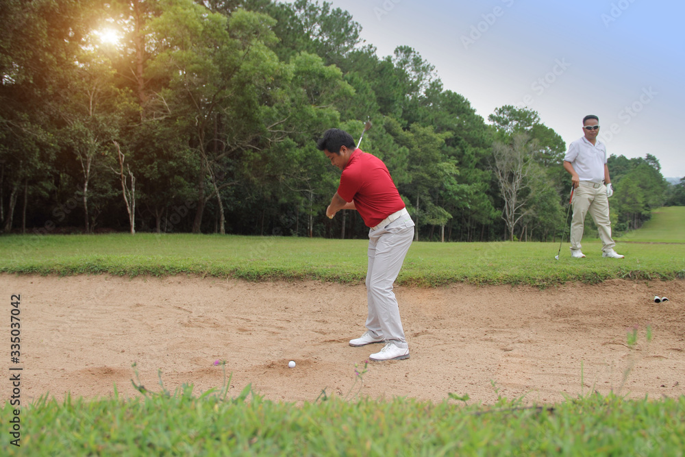 Golfer hitting the ball on the sand.
