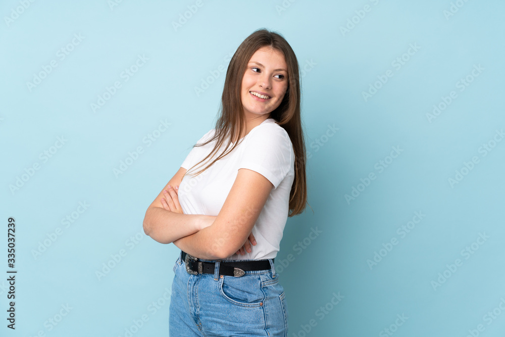 Teenager caucasian girl isolated on blue background with arms crossed and happy Teenager caucasian girl isolated on blue background with arms crossed and happy
