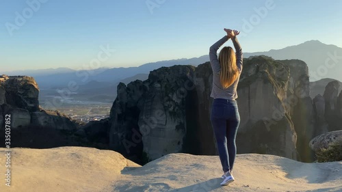 Young beautiful woman-tourist warming up at mountain peak