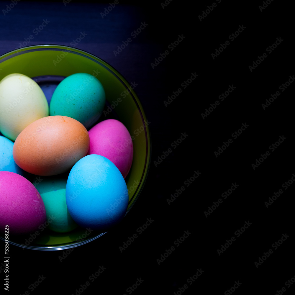Close up different colored eggs on the bowl on black background for Easter concept. Close up different colored eggs on the bowl on black background for Easter concept.