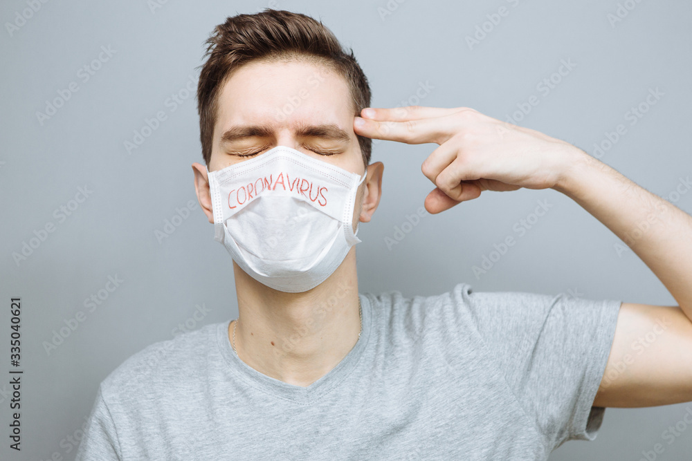 Portrait of a sick man wearing medical mask with coronavirus text at gray background. Coronavirus concept. Protect your health. Pandemic Portrait of a sick man wearing medical mask with coronavirus text at gray background. Coronavirus concept. Protect your health. Pandemic