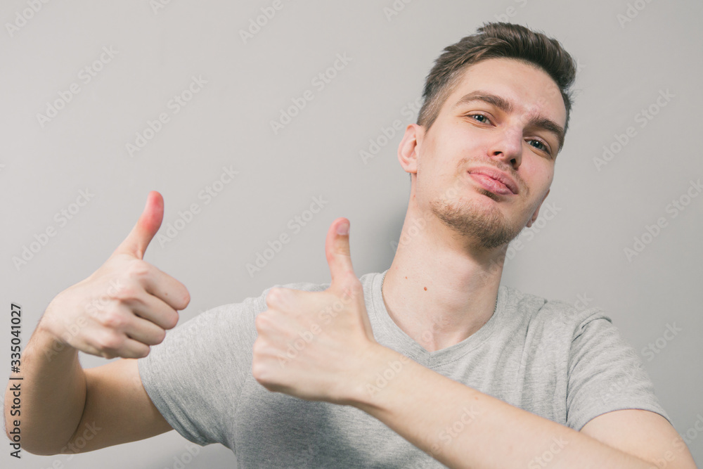 The young guy on a light background depicts different emotions The young guy on a light background depicts different emotions