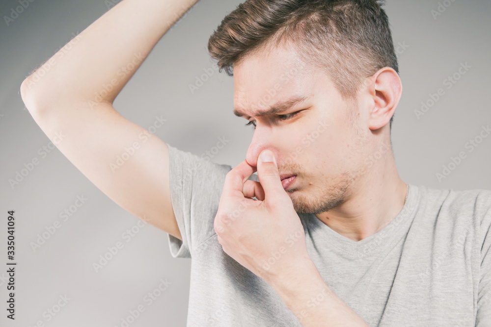 Young man sniffing an armpit Young man sniffing an armpit