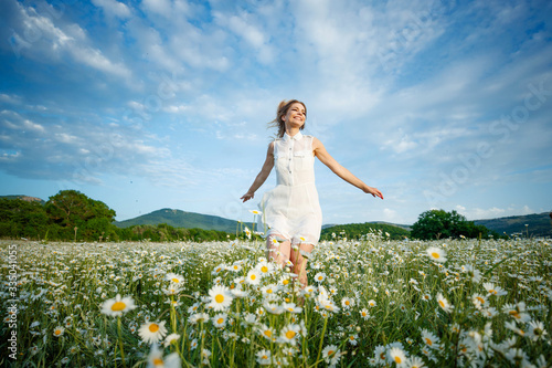 Woman in a field with flowers. Beautiful girl in a field with daisies.