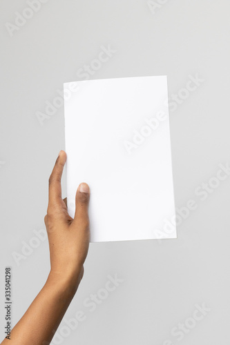 Woman of color holding and A5 or half letter size blank mockup. © TheCreativeBrigade