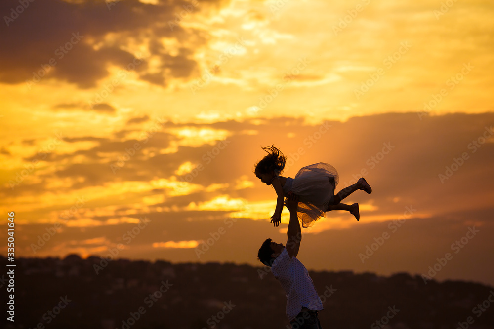 silhouette of dad throws daughter at sunset. silhouette of dad throws daughter at sunset.